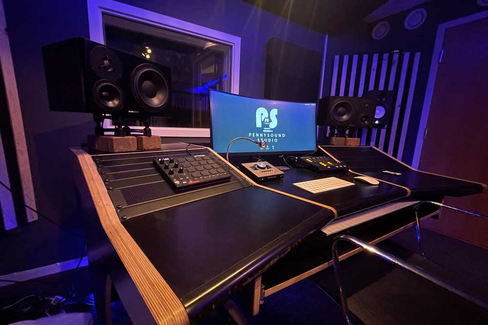 Interiör från Pennysound studio med mixerbord, monitorer och ett bildskärm. 